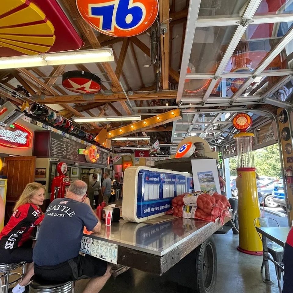 Diners sit at a counter made from a vintage truck, surrounded by gas station memorabilia.